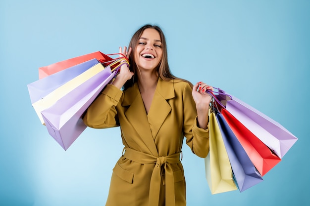 Belle femme tenant des sacs colorés isolés sur bleu