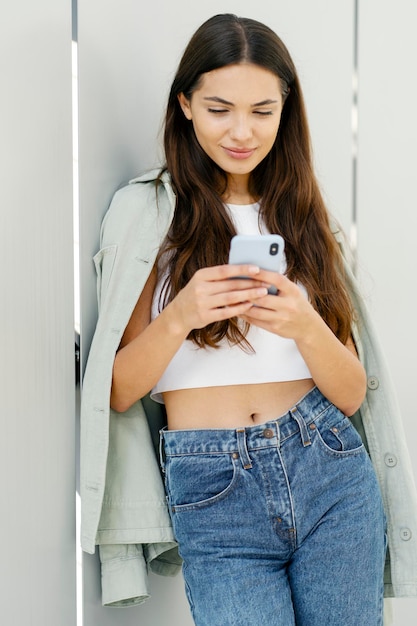 Belle femme tenant un smartphone à l'aide de la messagerie d'application mobile dans les médias sociaux