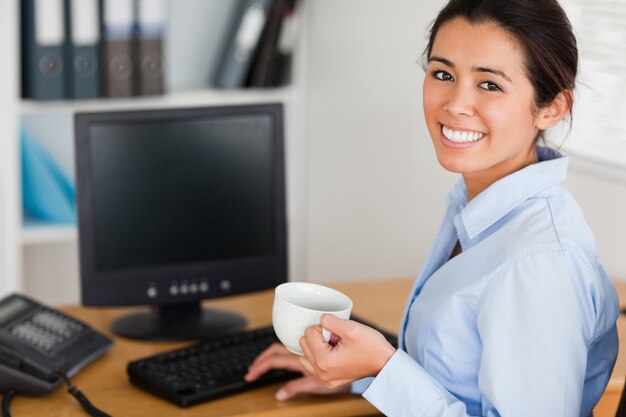 Belle femme tenant une tasse de café en position assise