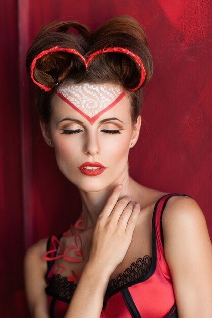 Belle femme tendre fermant les yeux posant en lingerie rouge.