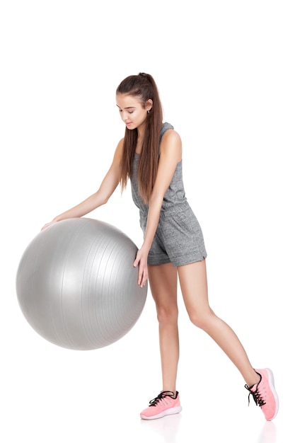 Belle femme en tenue de sport avec ballon de fitness isolé sur fond blanc