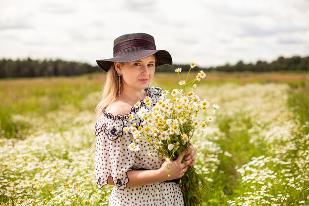 Belle femme sur le terrain avec des fleurs. Photo de haute qualité