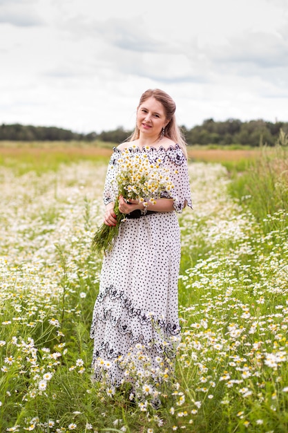 Belle femme sur le terrain avec des fleurs. Photo de haute qualité