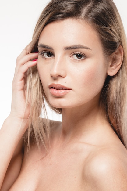 Belle femme touche son visage avec les doigts. portrait de visage bouchent studio sur blonde blanche. Prise de vue en studio. Isolé sur blanc.