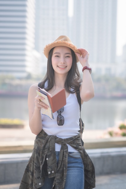 Belle femme touriste solo asiatique souriante et à la recherche de sites touristiques.