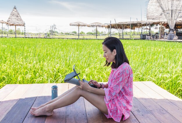 Belle femme travaillant sur ordinateur portable assis sur une terrasse en bois en plein air
