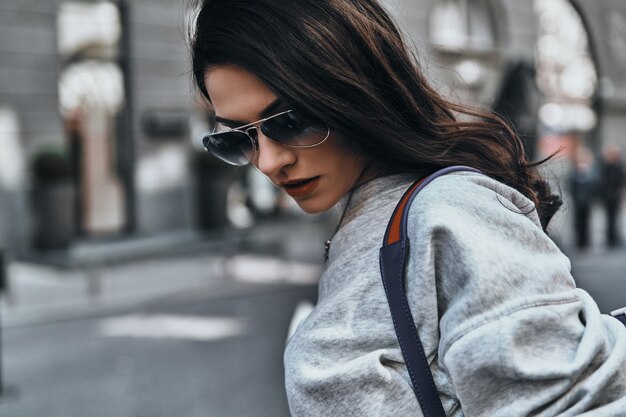 belle femme urbaine. Jeune femme séduisante à lunettes regardant vers le bas