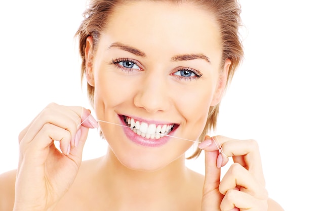 Photo belle femme utilisant un fil dentaire pour ses dents sur fond blanc