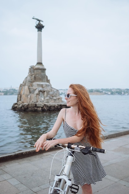 Belle femme à vélo Mode de vie et santé dans la ville Une jeune femme rousse joyeuse prend plaisir à se promener dans la ville