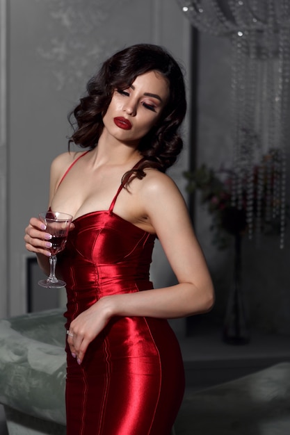 belle femme avec un verre à la main dans une robe rouge.