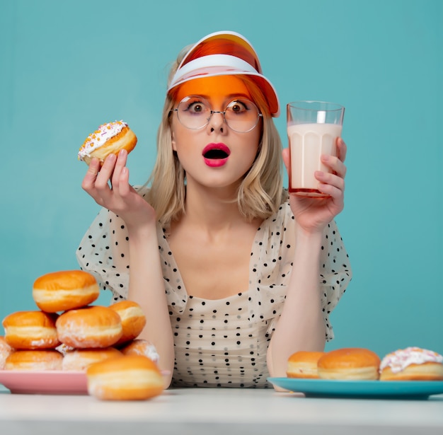 Belle femme en vêtements des années 90 avec des beignets et du lait