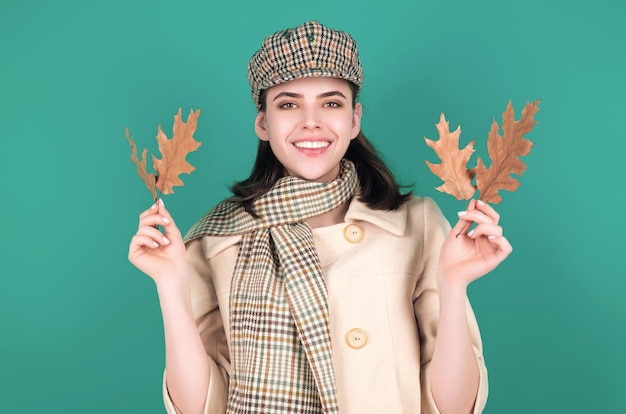 Belle femme en vêtements d'automne tenant des feuilles qui tombent posant dans le studio Gorgeuse mannequin brune avec une feuille d'érable jaune d'hiver Femme d'automme dans le studio Humeur d'automle