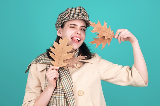 Belle femme en vêtements d'automne tenant des feuilles qui tombent posant dans le studio Gorgeuse mannequin brune avec une feuille d'érable jaune d'hiver Femme d'automme dans le studio Humeur d'automle