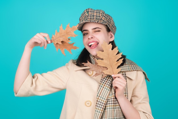 Une belle femme en vêtements d'automne tient les feuilles qui tombent posant dans le studio une magnifique mannequin brune