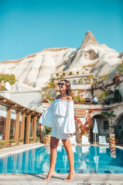 Belle femme en vêtements blancs posant près de la piscine de l'hôtel de Cappadoce