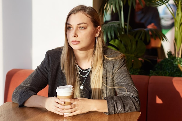 Belle femme en vêtements noirs assis seul dans un café