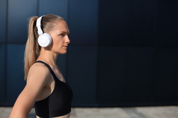 Belle femme en vêtements de sport et écouteurs à côté de l'appareil photo.