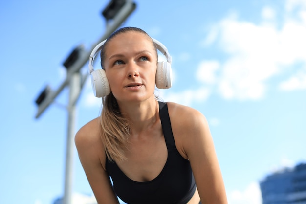 Belle femme en vêtements de sport et écouteurs à côté de l'appareil photo.