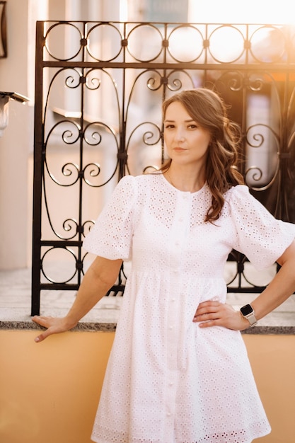 Une belle femme vêtue d'une robe blanche au coucher du soleil dans la ville Photographie de rue en soirée