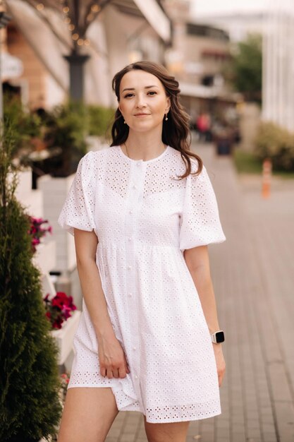 Une belle femme vêtue d'une robe blanche au coucher du soleil dans la ville Photographie de rue en soirée