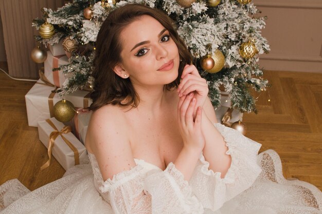 Belle femme vêtue d'une robe blanche sur le fond d'un arbre de Noël