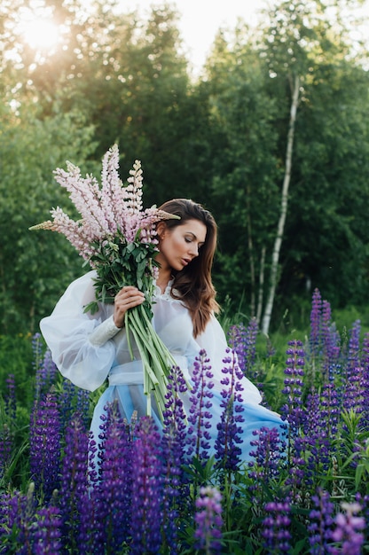 Belle femme vêtue d'une robe à fleurs lupins au coucher du soleil