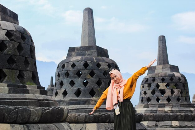 Une belle femme vêtue d'une robe orange pose au temple de Borobudur Le plus grand temple du monde