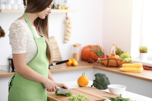 Une belle femme vêtue d'un tablier cuisine dans une cuisine ensoleillée.