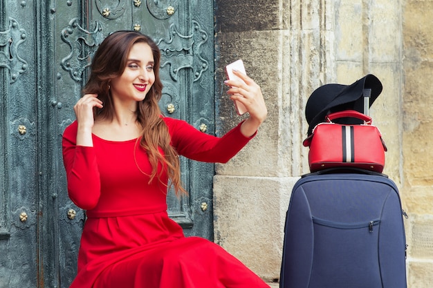 Belle femme voyageur avec une valise prend selfie