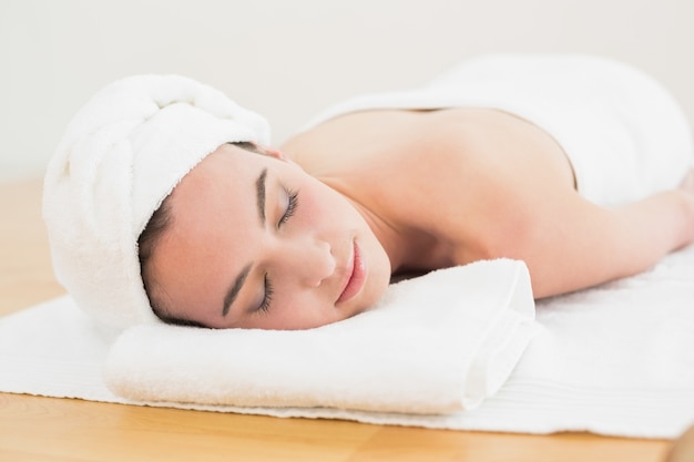 Belle femme avec les yeux fermés sur une serviette au spa beauté