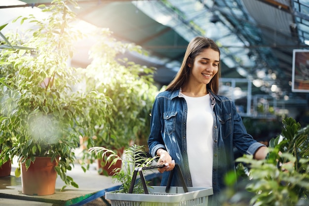 Belle fille achetant des plantes vertes dans un magasin Planifiant de surprendre sa mère avec un cadeau