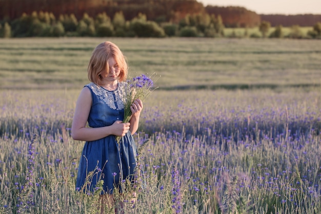 Belle fille adolescente dans le champ d'été avec bleuet