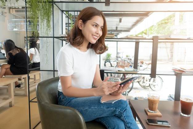 Belle fille d&#39;affaires travaillant avec tablette, smartphone et boire du café au café