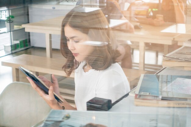 Belle fille d&#39;affaires travaillant avec tablette, smartphone et boire du café au café