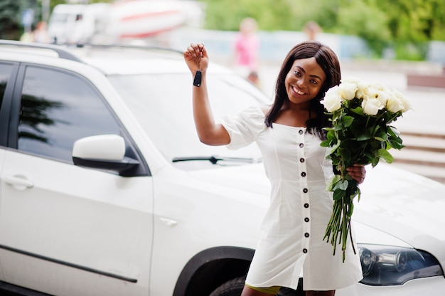 Belle fille afro-américaine dans une robe blanche avec des fleurs dans les mains