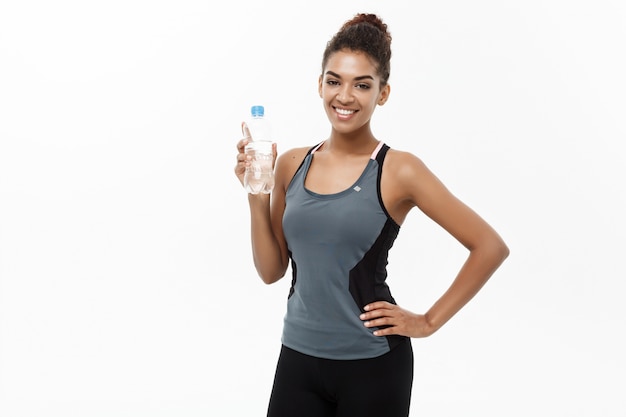 belle fille afro-américaine dans les vêtements de sport tenant une bouteille d&#39;eau en plastique après l&#39;entraînement.