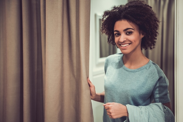 Belle fille afro-américaine est debout près de cabine d'essayage.