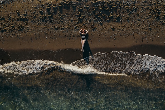 Belle fille allongée sur une plage de sable sur la vue de dessus de mer