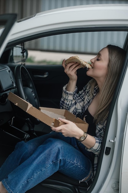 belle fille avec appétit mange de la pizza dans sa voiture