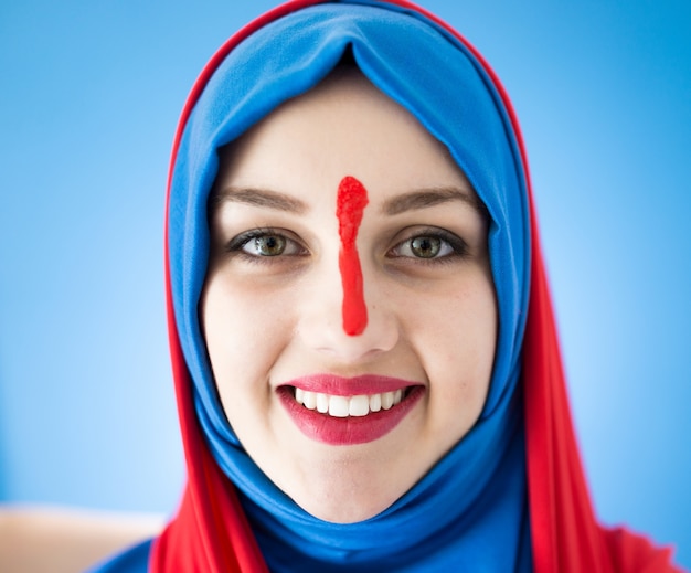 Belle fille arabe avec écharpe sur fond bleu