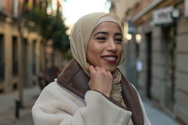 Belle fille arabe avec hijab à l'extérieur sur fond bleu