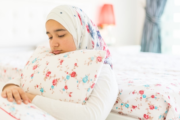 Belle fille arabe sur le lit dans la chambre moderne