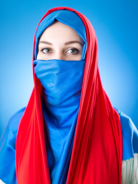 Belle fille arabe avec voile sur fond bleu