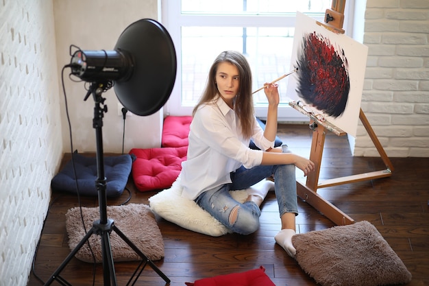 Belle fille artiste au travail dans un studio blanc créatif