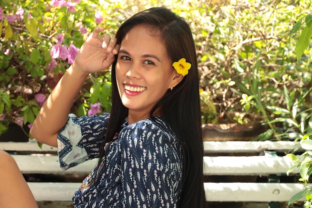 Photo une belle fille asiatique assise sur un banc avec des fleurs.