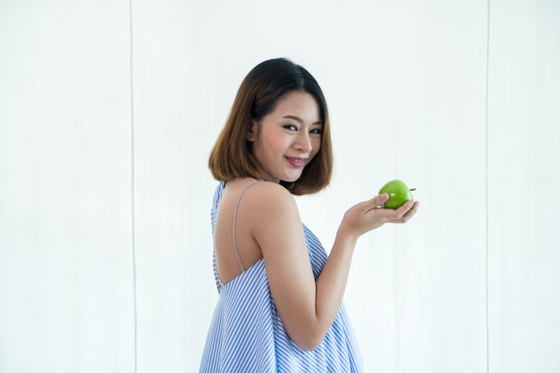 Une belle fille asiatique enceinte. Elle tient une pomme verte.