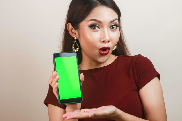 La belle fille asiatique est choquée par le smartphone avec une chemise rouge