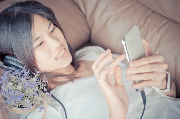 Belle fille asiatique est écouter de la musique sur smartphone