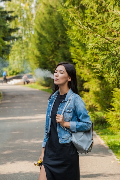 Belle fille asiatique fume dans un lieu public.