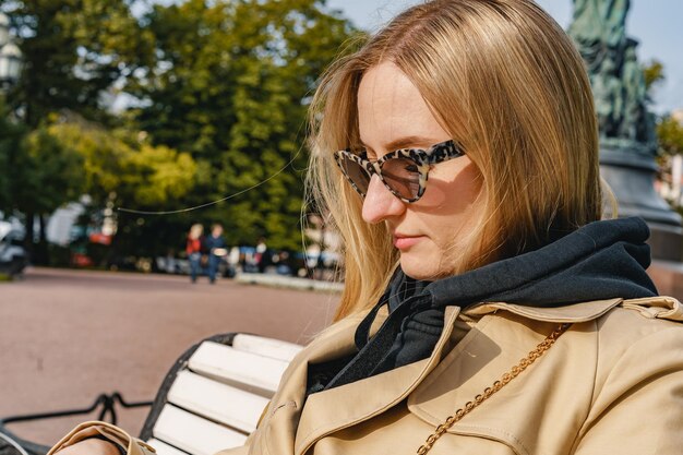 Belle fille assise sur un banc à lunettes de soleil